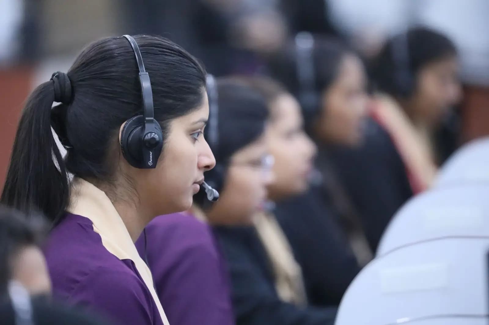 Row of call center agents wearing headsets